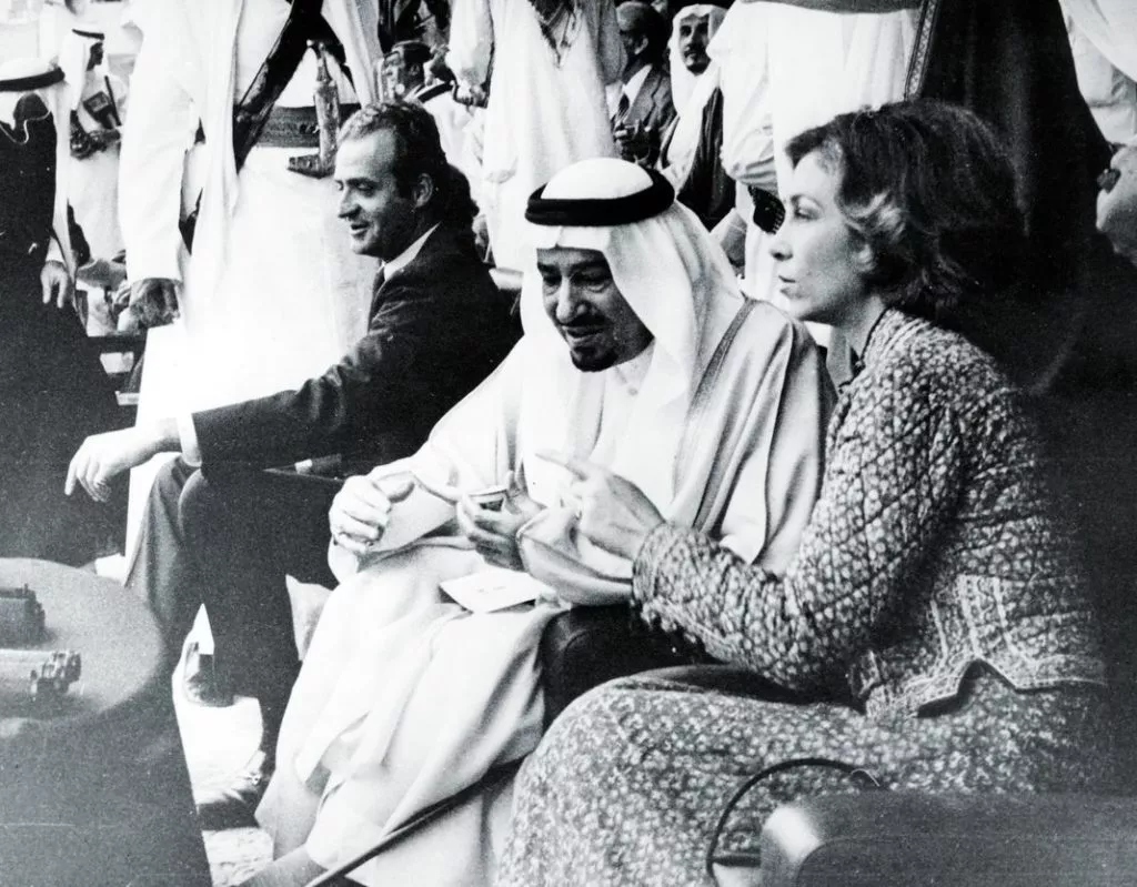 Королева Испании София разговаривает с королем Саудовской Аравии Халедом, а король Хуан Карлос наблюдает за верблюжьими гонками на ипподроме