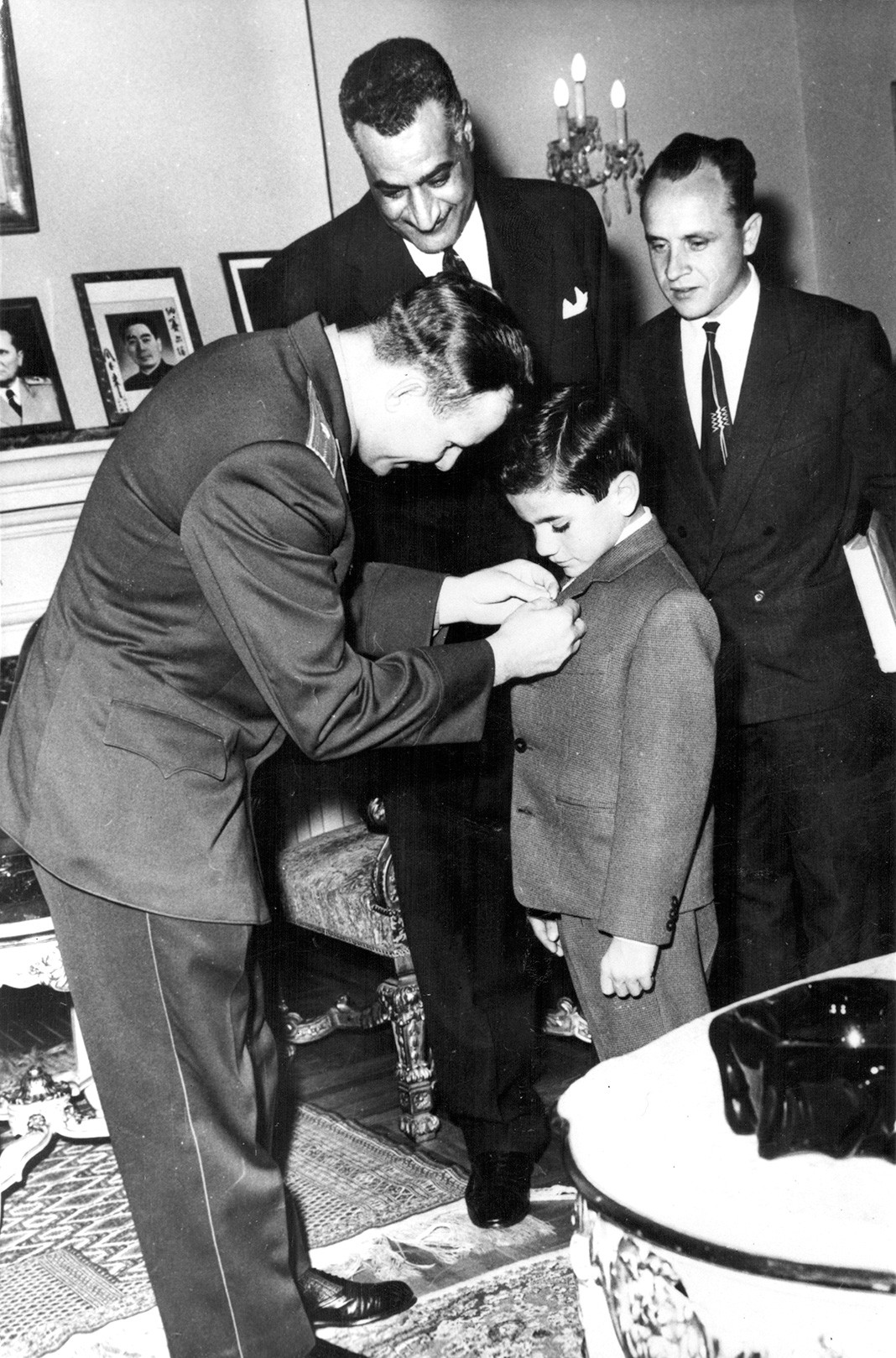 Прикалывает значок к лацкану пиджака младшего сына президента Египта Насера во время визита в Объединенную Арабскую Республику, Каир, Египет, 6 февраля 1962 г.