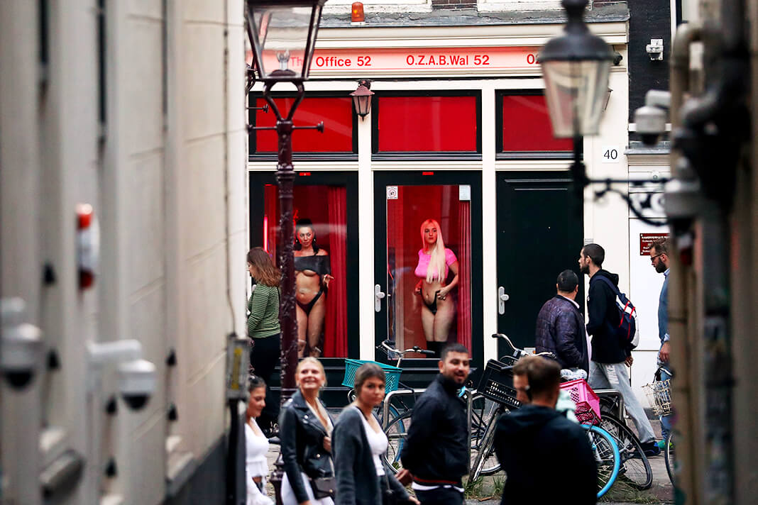 Проститутки стоят за окнами в Районе Красных фонарей в Амстердаме