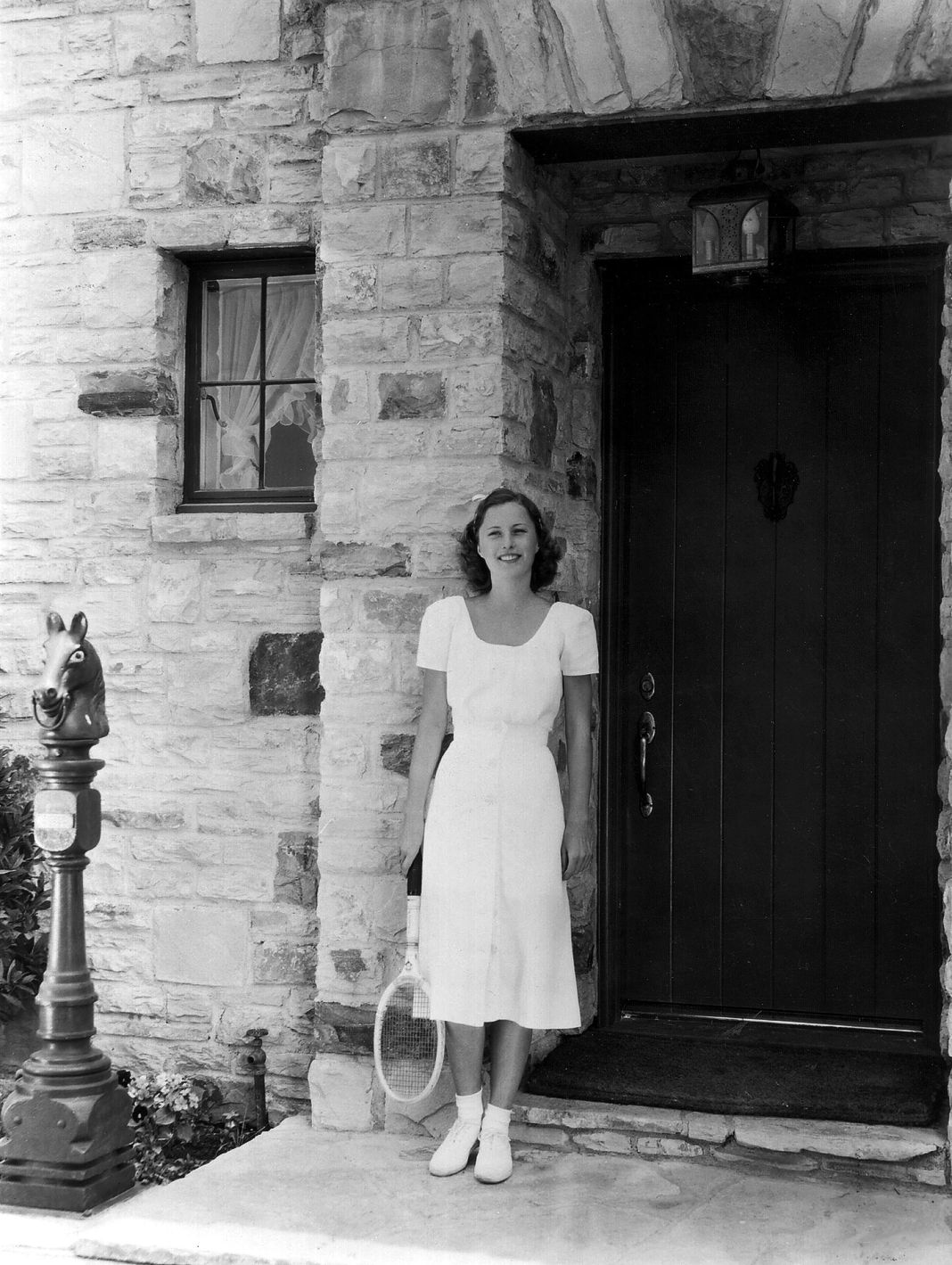 Барбара Стэнвик (1907–1990), рыжеволосая американская звездная актриса, стоит у входной двери своего дома на ранчо.