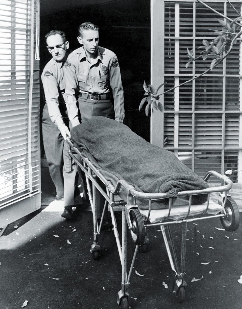 Медицинские работники выносят тело Мэрилин Монро из ​​ее дома.