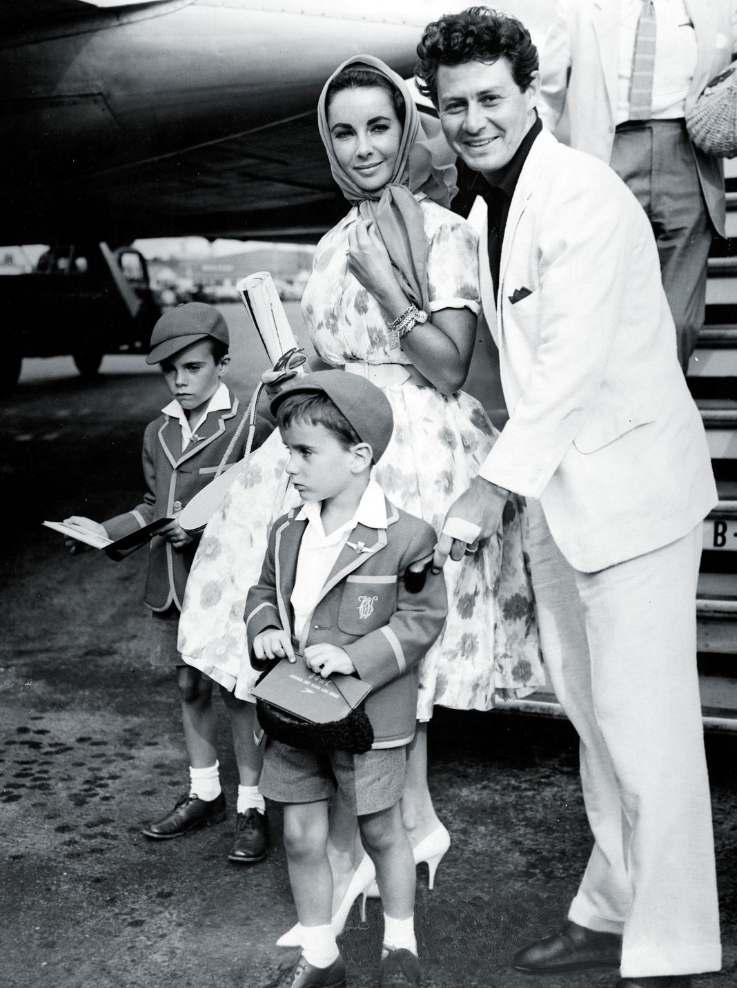 Актриса Элизабет Тейлор и ее муж, певец Эдди Фишер, на снимке со своими детьми Кристофером и Майклом выходят из своего самолета.
