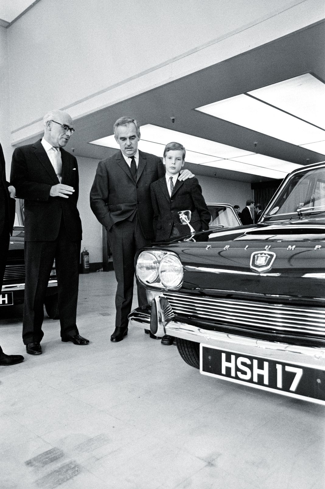 Дональд Стоукс, приветствует принца Монако Ренье III и его сына принца Альберта в автосалоне British Leyland