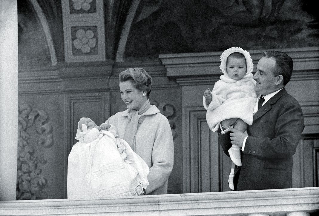 Ренье III, принц Монако, держит Каролину, принцессу Ганноверскую, а жена, американская актриса Грейс Келли, принцесса Монако, представляет принца Альберта II