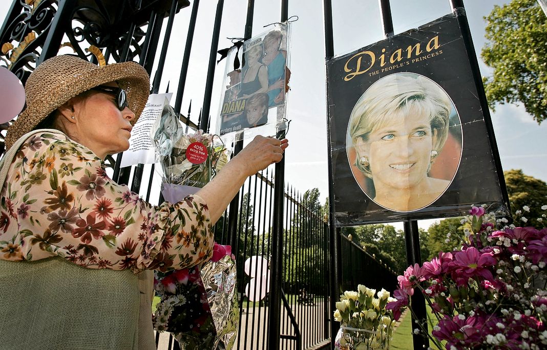 Женщина воздает дань памяти принцессе Диане, принцессе Уэльсской, у ворот Кенсингтонского дворца в Лондоне
