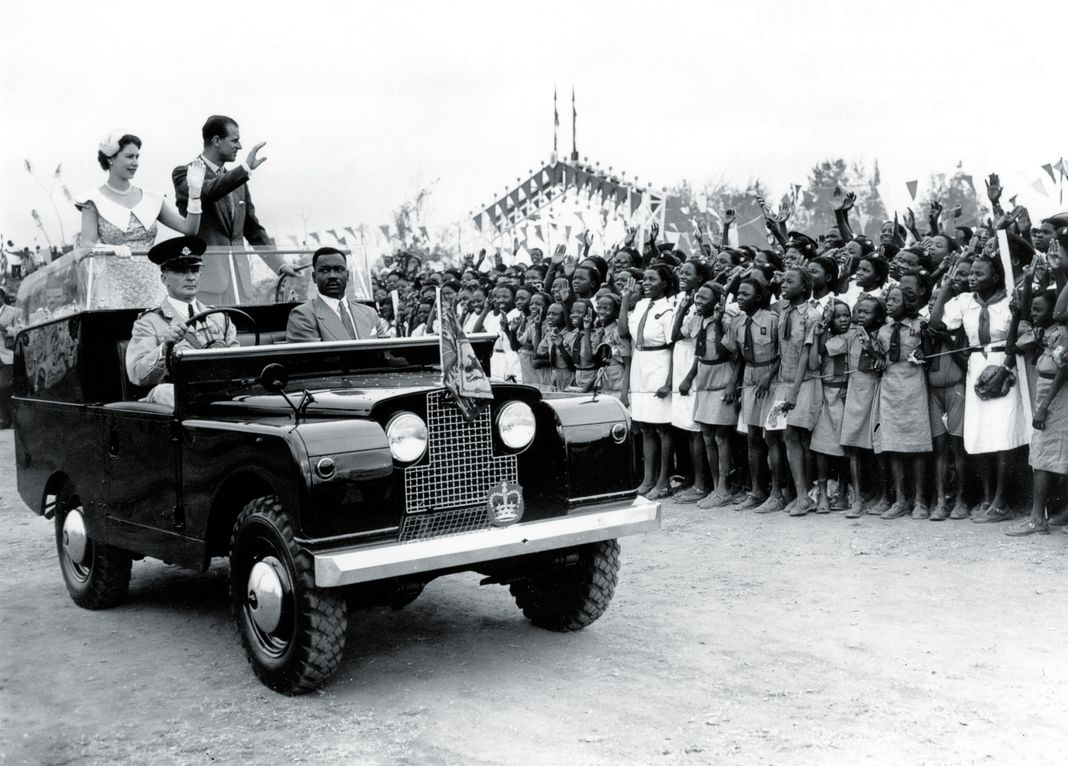 Королева Елизавета II и принц Филипп машут толпе школьников на митинге, проходившем на ипподроме в Ибадане