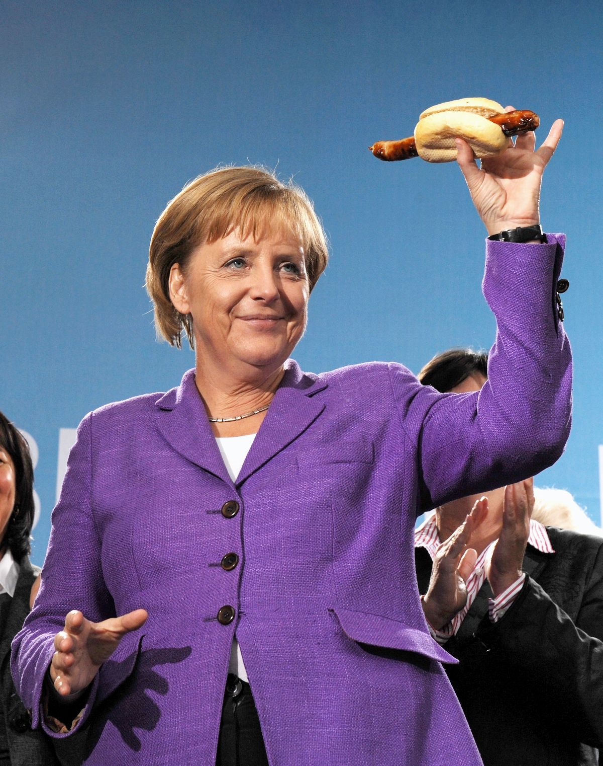 Канцлер Германии Ангела Меркель держит настоящую тюрингскую колбасу на гриле
