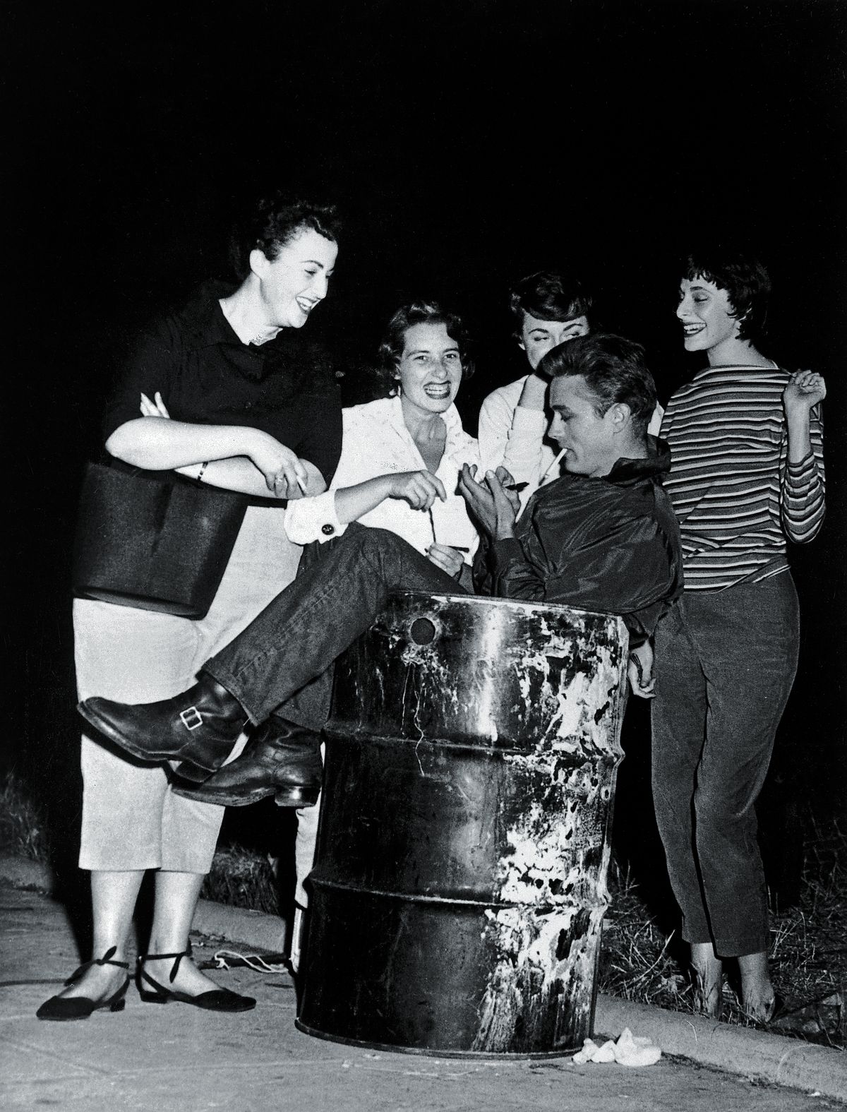 Джеймс Дин раздает автографы группе фанатов, сидя в мусорном баке
