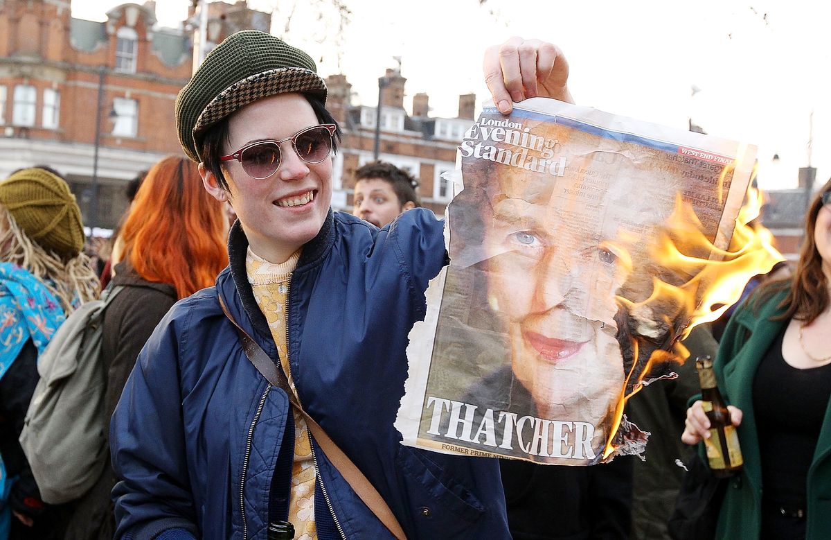 Женщина сжигает первую полосу газеты с изображением бывшего премьер-министра Великобритании Маргарет Тэтчер
