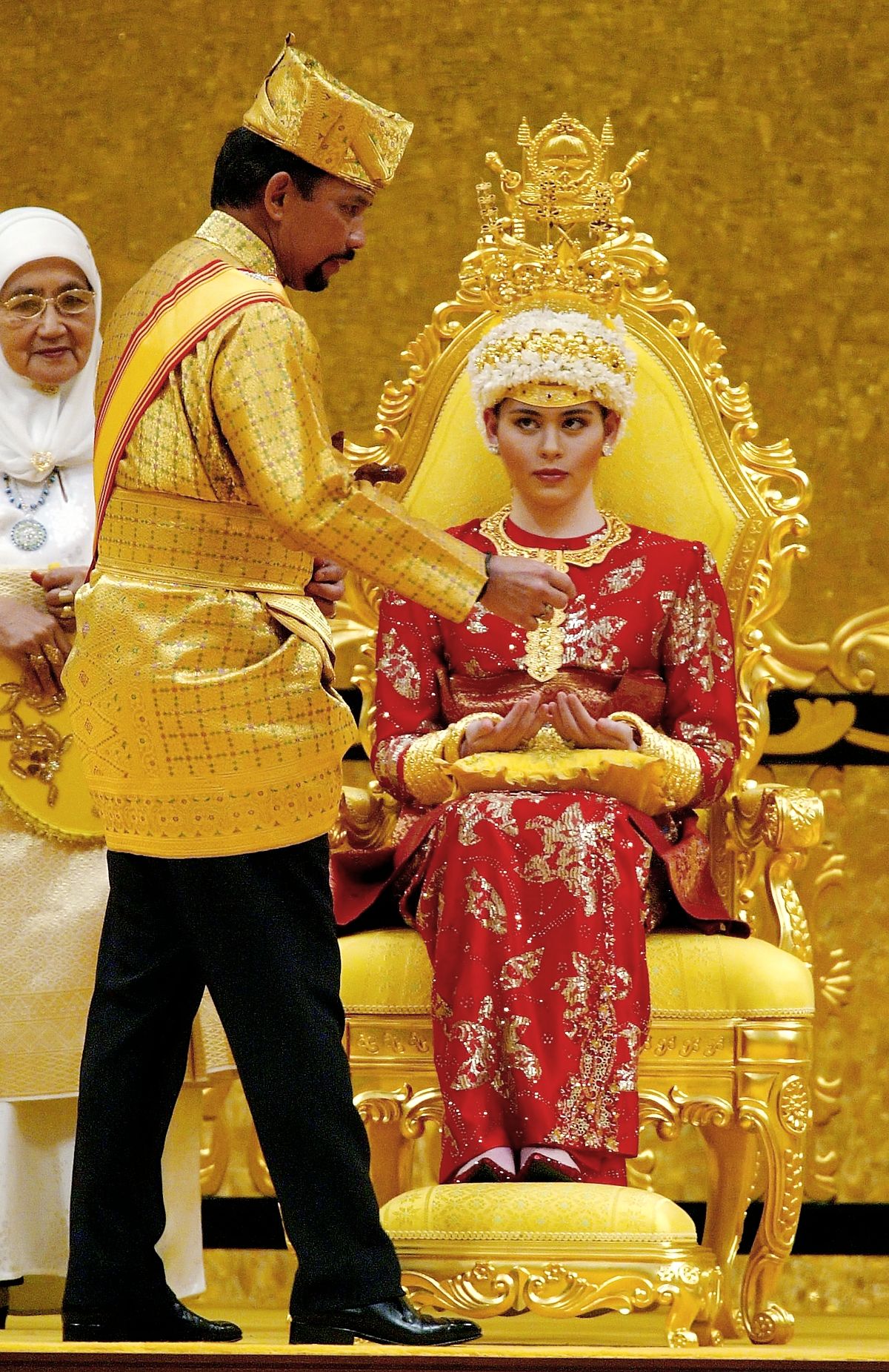 Султан Брунея намазывает руки принцессе Саре Саллех травами и пастами как традиция перед свадебной церемонией