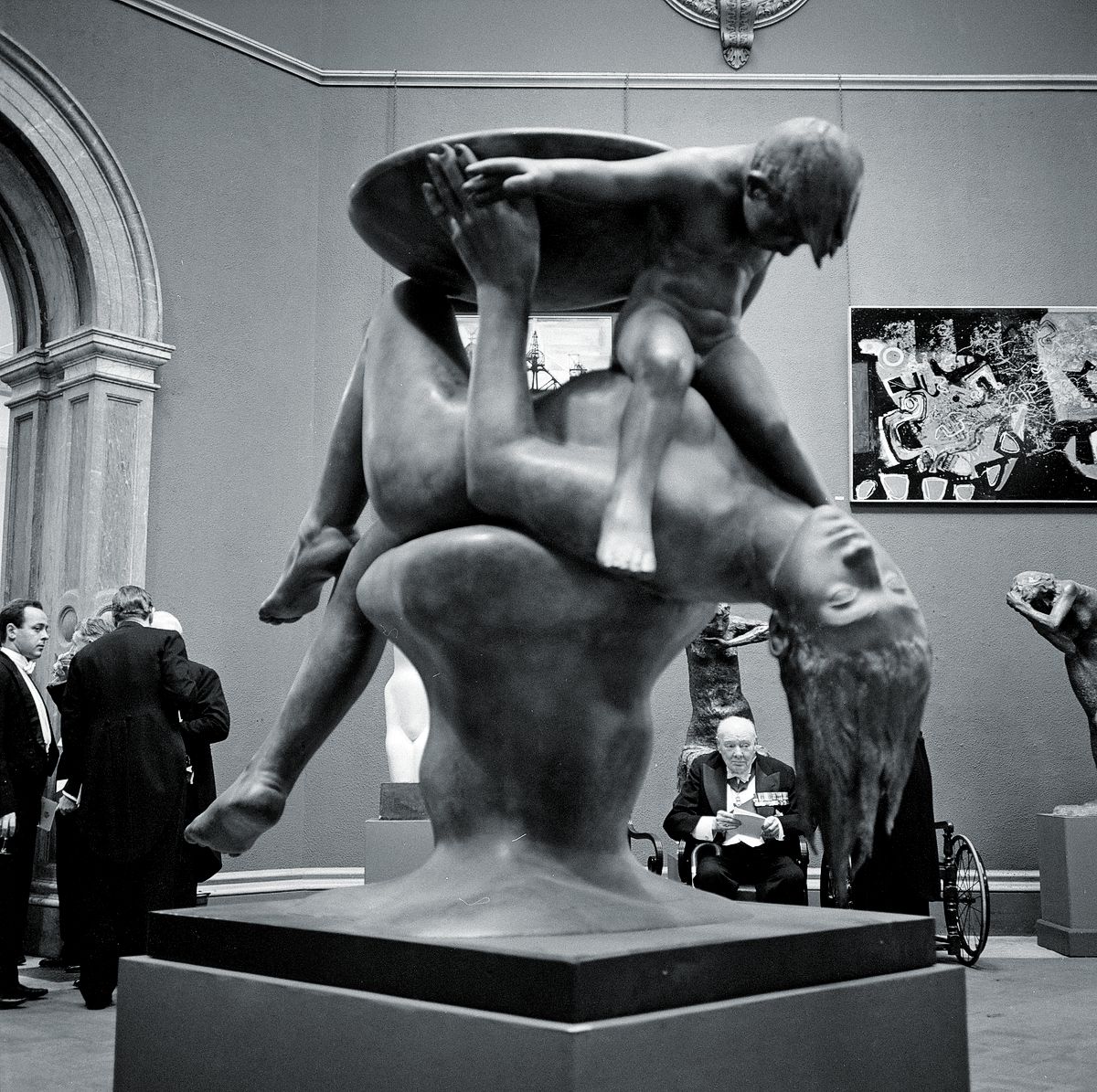 Уинстон Черчилль сидит в кресле на выставке картин и скульптур